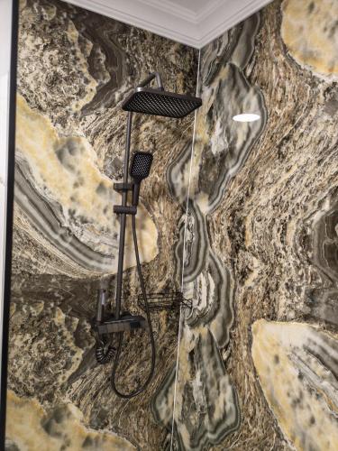 a shower in a bathroom with a stone wall at Terra Ștrand Residence Ștei in Doctor Petru Groza
