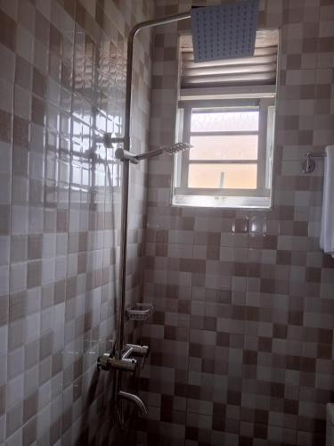 una ducha en un baño alicatado con ventana en Ayeba Zion Hotel, en Fort Portal
