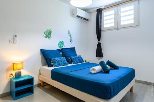 Un dormitorio con una cama azul y una ventana. en Kayna, en Sainte-Luce