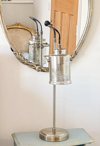a metal lamp on a table in front of a mirror at PRIMROSE COTTAGE, Sleeps 5, Stylish Cottage, Central, Close to Beach, shops and restaurants in Beer