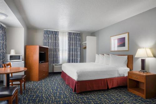 a hotel room with a large bed and a table at SureStay Plus Hotel by Best Western Lethbridge in Lethbridge