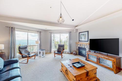 a living room with a tv and a couch and a table at Hilltop Hideaway - Legacy 401AB in Big White
