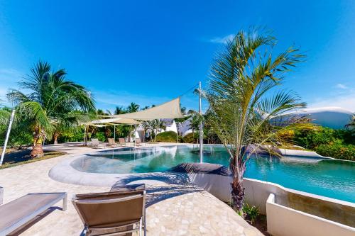 Una piscina en un resort con sillas y palmeras. en Lion Fish Retreat at Swan Villas -Gold Standard Certified, en Maya Beach
