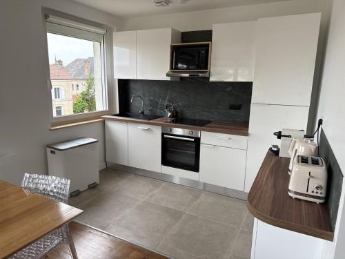 a kitchen with white cabinets and a table and a window at Le Trente 9 in Neufchâteau