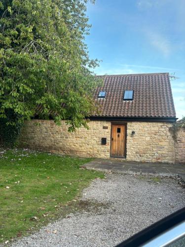 a brick building with a wooden door and a tree at Welsh Apple Barn in Chepstow