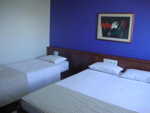 two beds in a room with a blue wall at Bristol Exceler Campo Grande in Campo Grande