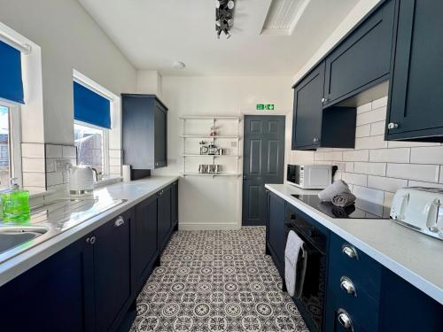 a kitchen with blue cabinets and a white refrigerator at The Whitley Maisonette, Luxury Family Holiday Home in Whitley Bay
