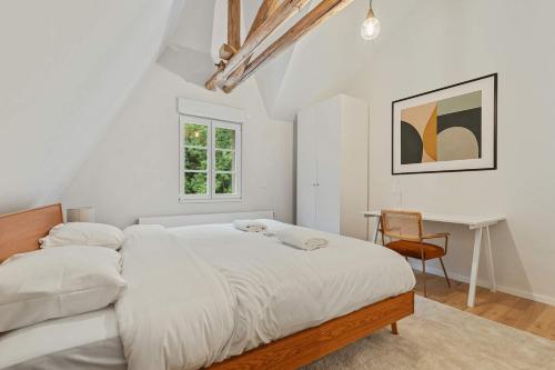 a white bedroom with a large bed and a desk at Chic One-Bedroom Near Luxembourg City Center in Luxembourg