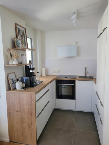 a kitchen with white cabinets and a wooden counter top at StyLE Apartment - perfekt für Messe, Flughafen, S-City in Leinfelden-Echterdingen