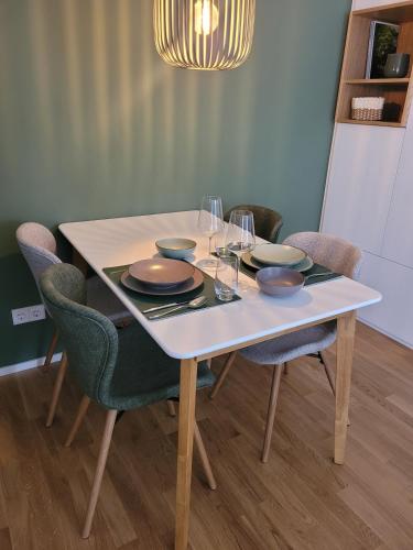 a table with plates and bowls on it with chairs at StyLE Apartment - perfekt für Messe, Flughafen, S-City in Leinfelden-Echterdingen
