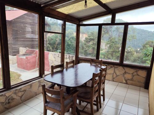 a table and chairs in a room with windows at Cabañas la garita2 in San Cristóbal de Las Casas