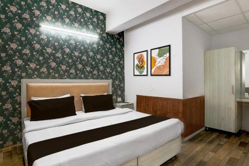 - une chambre avec un grand lit et du papier peint floral dans l'établissement Hotel O Square Residency, à Rājpur