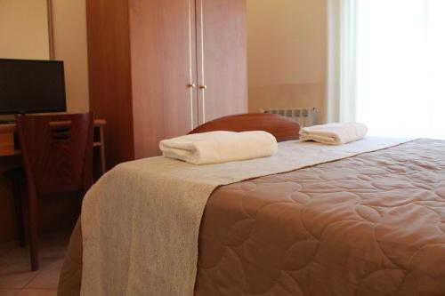 a bedroom with a bed with two towels on it at Hotel Ristorante Benigni in Campagnano di Roma