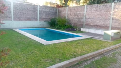a swimming pool in a yard with a brick wall at Colina Garden departamento in Victoria