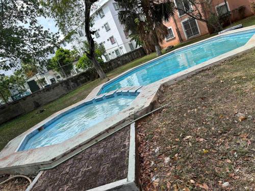 une piscine vide dans l'herbe devant un bâtiment dans l'établissement Downtown Cancun Accommodation, à Cancún
