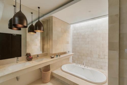 a bathroom with a tub and a large mirror at Akhyana Village in Jimbaran