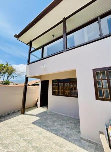 a white house with glass windows and a patio at Chalés em Ilhabela 01 in Ilhabela