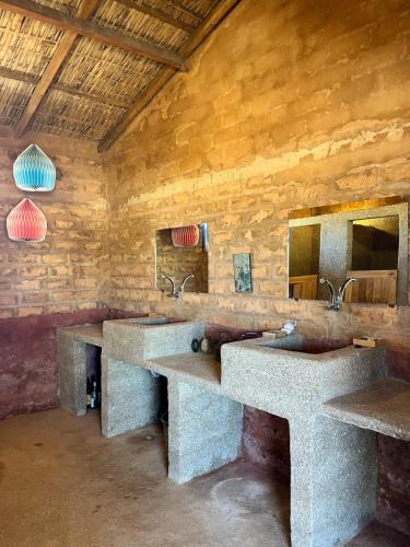 une salle de bain avec deux lavabos et deux miroirs dans l'établissement Mbin Maak du Saloum, à Mar Lodj