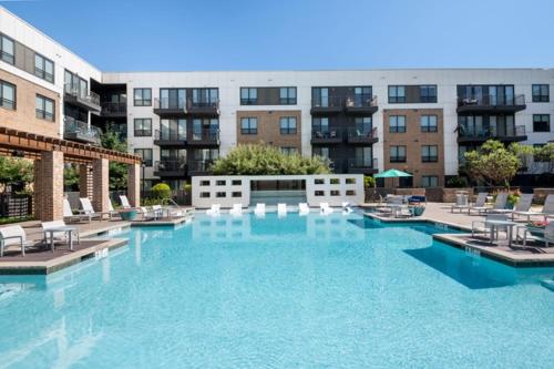 a large pool of blue water with chairs and buildings at Dallas Loft-Your getaway home in Dallas