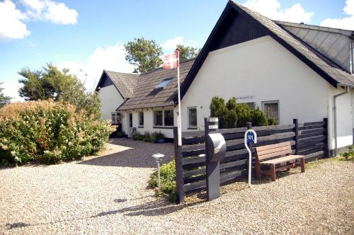 a white building with a bench in front of it at Henne Strand Ferie Accommodation in Hennebjerg