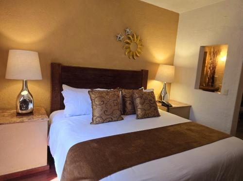 a bedroom with a bed with pillows and two lamps at Casa Aurea Hotel Boutique in Morelia