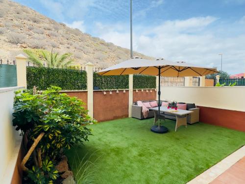 a patio with an umbrella and a table at Bright Retreat with Lush Outdoor Space in Palm-Mar