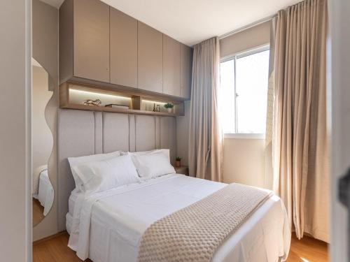 a bedroom with a white bed and a window at Apartamento sofisticado c vaga e vista Arena MRV in Belo Horizonte