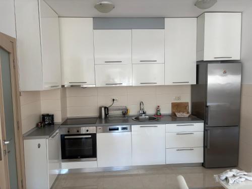 a kitchen with white cabinets and a stainless steel refrigerator at Forte Mare Apartment in Podgorica