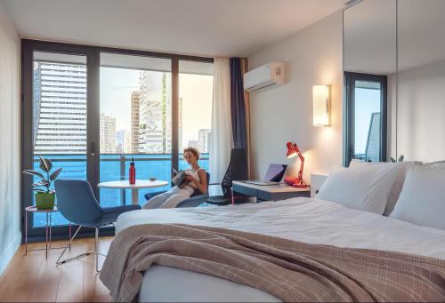 una habitación de hotel con una cama y dos mujeres sentadas en sillas en PANORAMA Luxury Hotel Batumi, en Batumi