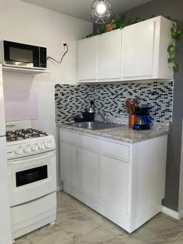 a kitchen with white cabinets and a stove at Casa Vagon Villa Janer in San Lorenzo