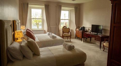 a hotel room with two beds and a desk and a television at Hill House Cashel in Cashel
