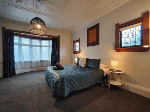 a bedroom with a bed and a large window at Heritage & Heart by the Park in Invercargill