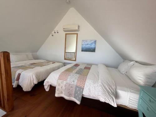 a attic bedroom with two beds and a window at Le Chalet d'Isabelle in La Conception