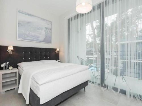 a bedroom with a large bed and a large window at Comfortable holiday home with garden, summer pool in Pobierowo