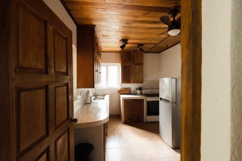 Il comprend une cuisine dotée de plafonds en bois et d'un réfrigérateur blanc. dans l'établissement The Boom Cottage, à Aposentillo