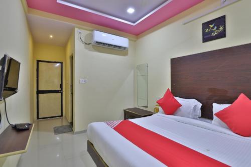ein Schlafzimmer mit einem großen Bett mit roten Kissen in der Unterkunft Hotel O D K Guest House in Anand