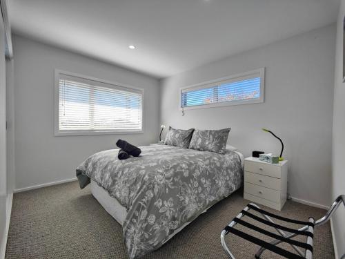 ein Schlafzimmer mit einem Bett, einem Stuhl und zwei Fenstern in der Unterkunft Glenwood Cottage in Kennington