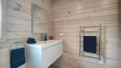 a bathroom with a white sink and wooden walls at Luxe on the Lake Front in Te Anau