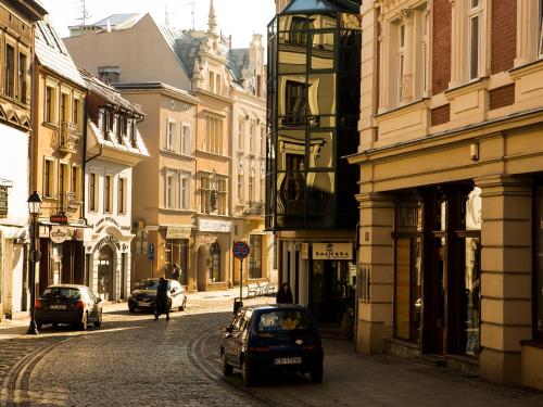 a small car parked on a street with buildings at Softly Residence in Bydgoszcz