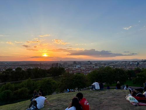 a group of people sitting on a hill watching the sunset at Acogedora habitación en barrio madrileño con encanto in Madrid