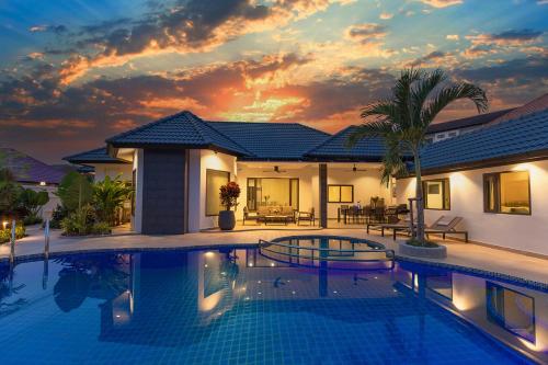 a villa with a swimming pool at sunset at Pattaya Hill minutes from the beach and City Pattaya in Nong Prue
