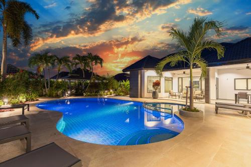a large blue swimming pool in a yard with palm trees at Pattaya Hill minutes from the beach and City Pattaya in Nong Prue