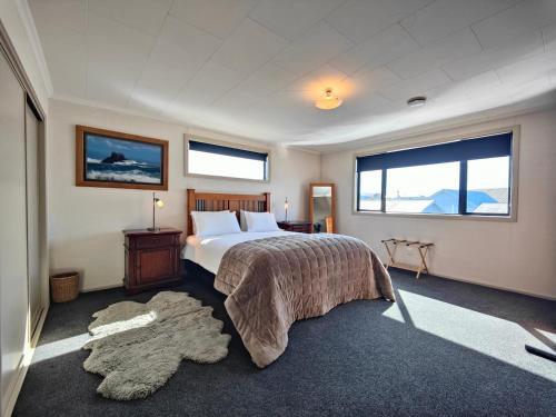a bedroom with a large bed and two windows at Korimako Sea View Sanctuary in Riverton