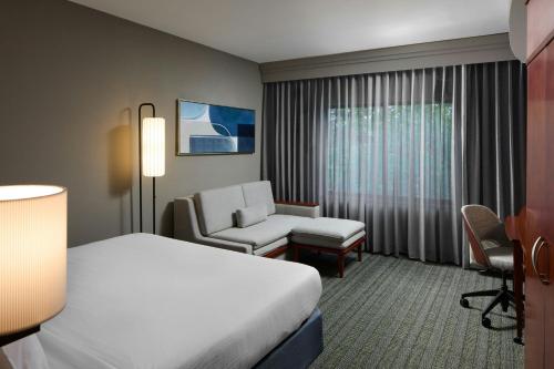 a hotel room with a bed and a chair at Courtyard by Marriott Waldorf in Waldorf