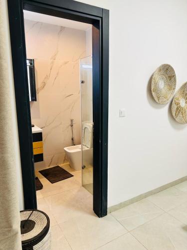 a bathroom with a glass door leading to a toilet at Studio meublé premium in Dakar