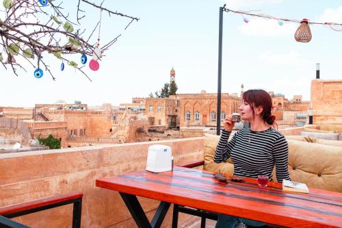 a woman sitting at a table talking on a cell phone at Mons Masius Hotel Teras in Midyat