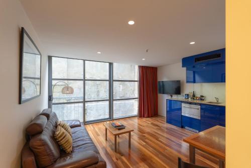 a living room with a couch and a kitchen with blue cabinets at Salamanca Wharf Hotel in Hobart