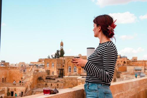 a woman standing on a ledge looking at a city at Mons Masius Hotel Teras in Midyat