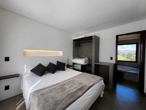 a bedroom with a large white bed with a window at chalé mantiqueira in Gonçalves