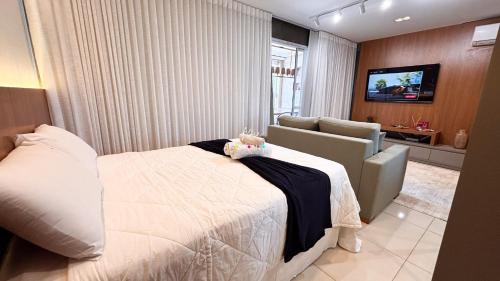 a bedroom with a bed and a couch and a television at #2905# Flat incrível– Lounge 22 | Setor Oeste in Goiânia